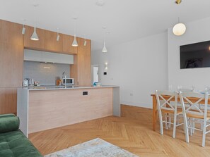 Eine moderne Küche mit Holzschränken, einer zentralen Kochinsel und Pendelleuchten.