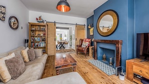 Ein Wohnzimmer mit Sofa, Couchtisch, Bücherregal und Kamin.