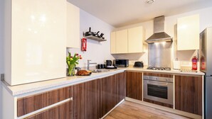 Une cuisine moderne avec des meubles en bois, une hotte en acier inoxydable, un four encastré et un four à micro-ondes.