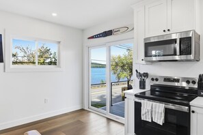 Una cocina con vistas a un lago, una estufa, horno, microondas y un juego de cuchillos.