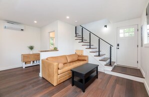Ein modernes Wohnzimmer mit einer Couch, einem Couchtisch und einer Treppe mit Geländer.