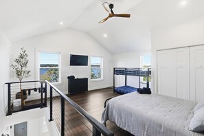 Un dormitorio amplio con una cama grande, un televisor instalado en la pared y un balcón con vistas.