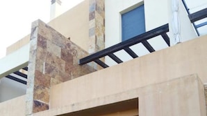 A modern building with a stone facade, a flat roof, and a glass door entrance. - Charming Apartment With Garden in Almeria (Vera)