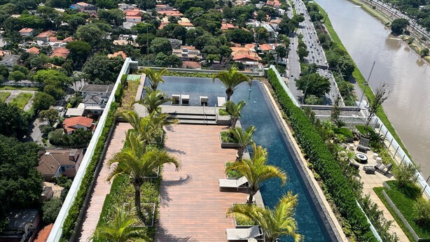 An aerial view of a resort with a swimming pool, lounge chairs, and a river. - Best View in SP - 62 m2 Apartment - 10 min from Butantã Metro Station (Yellow Line) (São Paulo)