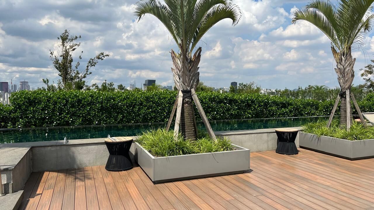 Een dak terras met een zwembad, palmbomen en een stadsbeeld op de achtergrond.