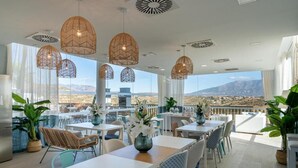 A modern dining area with tables and chairs, large windows, and hanging light fixtures. - Casa Banderas - 2 BR (6p) - Pool view & mountains - La Cala De Mijas (Cala de Mijas)