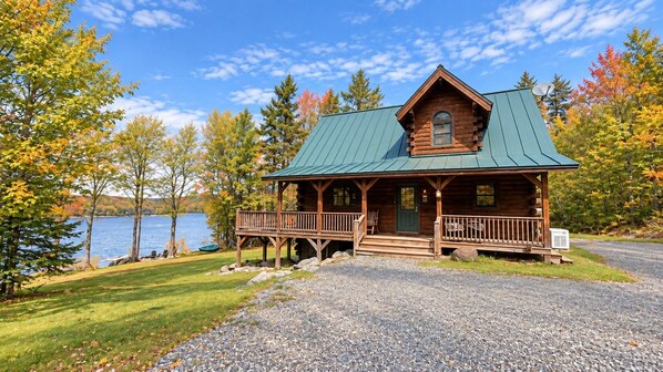 A cabin with a porch, a door, and a window.