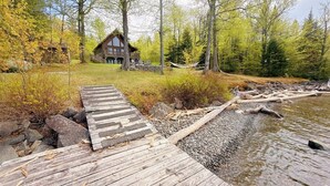 A wooden dock leading to a cabin surrounded by trees and a body of water.