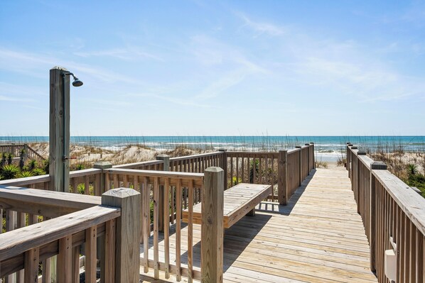 A wooden boardwalk leading to a beach with a clear sky. - Ocean View Top Floor Condo | Pool + Easy Beach Access (Emerald Isle)