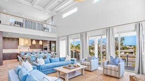 Un vaste espace de vie comprenant un grand canapé, une table basse et un coin repas avec des chaises.