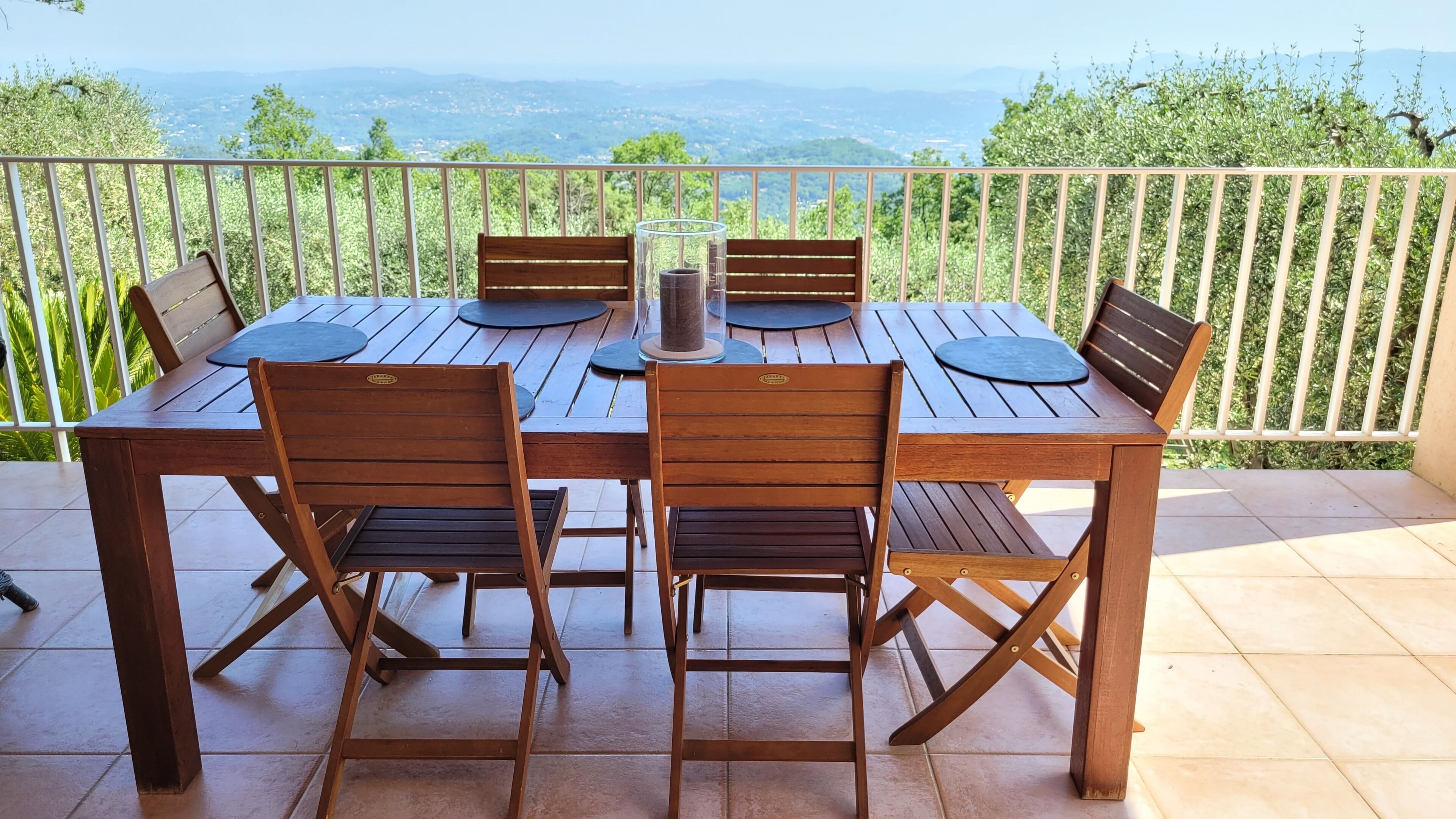 Une table et des chaises en bois sur un balcon offrant une vue sur le paysage.