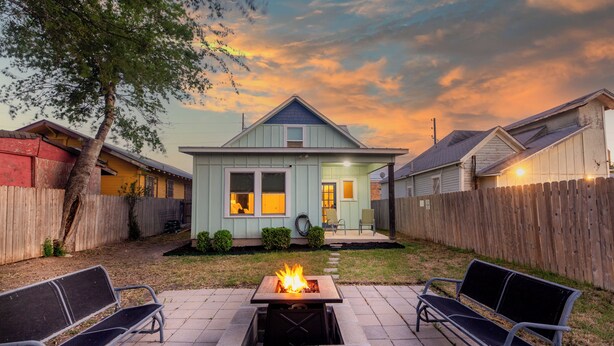 Ein Haus mit Feuerstelle im Garten, einer überdachten Terrasse und einem eingezäunten Grundstück.