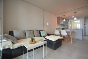 A modern living room with a sofa, a small table, and a dining area with chairs. - Las Arenas 197 - Two Bedroom Apartment, Sleeps 5 (Punta del moral)