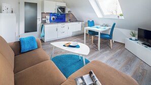 A compact living space with a kitchenette, a dining area, and a seating area with a sofa and a table. - Vacation apartment "Tillmanns Pusteblume" in Norddeich - quiet & close to the beach (Norden)