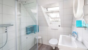 A modern bathroom with a glass shower enclosure, a small toilet, and a sink with a mirror. - Vacation apartment "Tillmanns Pusteblume" in Norddeich - quiet & close to the beach (Norden)