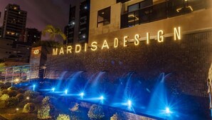Un bâtiment sur lequel on peut lire l’inscription « MARDISADESIGN » et devant lequel se trouve un élément décoratif aquatique.