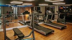 Une salle de sport équipée de tapis de course, de vélos elliptiques et d'appareils de musculation.