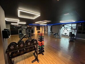 Una palestra con pavimenti in legno, attrezzature per sollevamento pesi e illuminazione moderna.