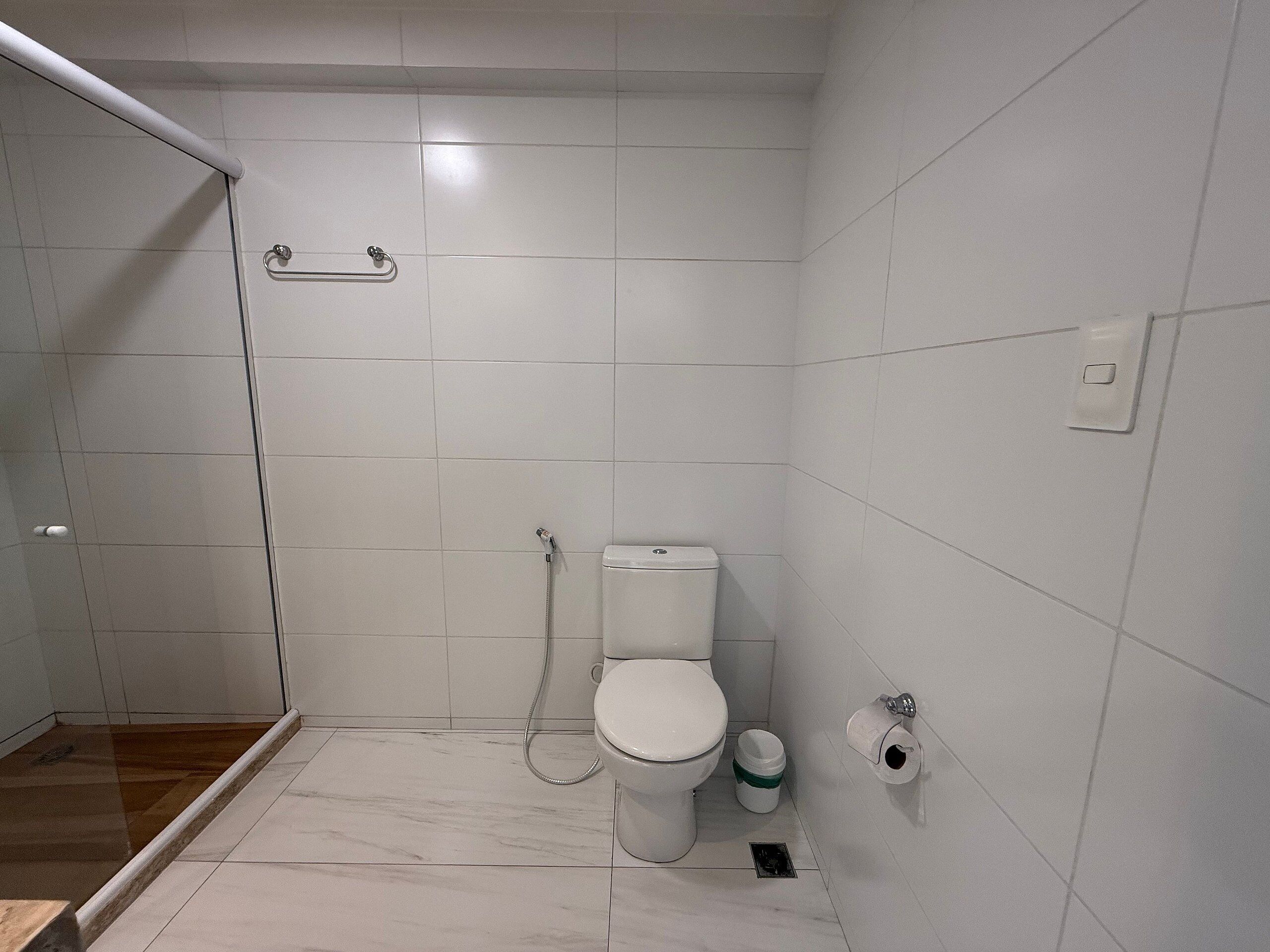 A bathroom with a toilet, shower, and a marble floor.