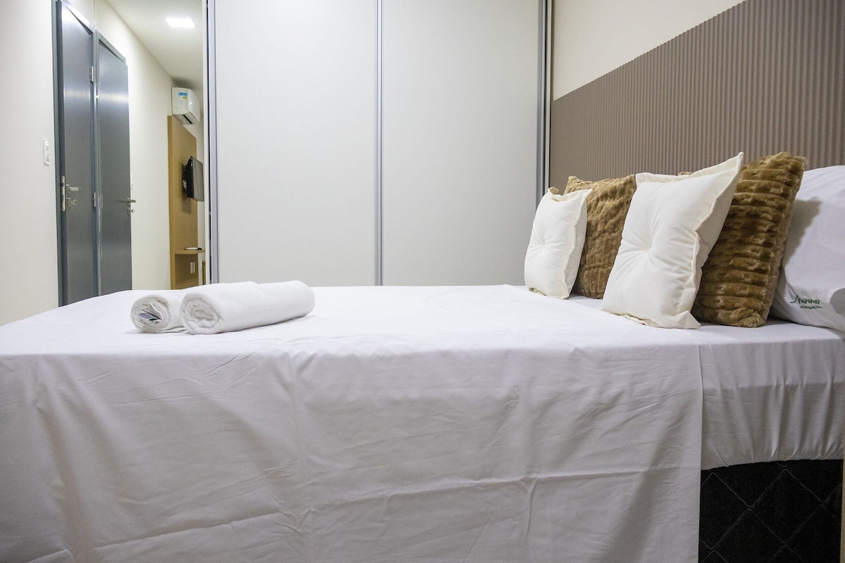 Una habitación de hotel con una cama bien hecha, un espejo y un televisor montado en la pared.
