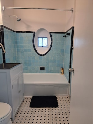 A bathroom with a bathtub, a window, a toilet, and a sink. - Phenomenal Studio - Steps to Beach - Great Views - Historic - terrific stay (Surfside)