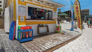 Ein Kiosk direkt am Strand mit einem Schild, das die Mietpreise für Liegen, Sonnenschirme und Handtücher ausweist.