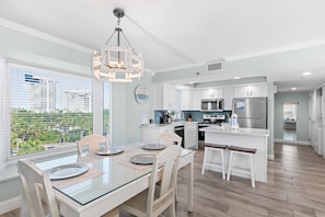 A modern kitchen with a dining area, large windows, and a view of the city.
