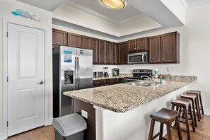Eine Küche mit Granit-Arbeitsplatten, Edelstahlgeräten, Holzschränken und einer weißen Tür.