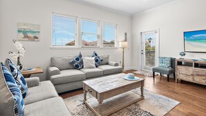A living room with a grey sofa, a wooden coffee table, and a view of the beach through large windows. - ☀️Private Beach Access | Pool+Hot Tub | Walk to Beach | Alerio D301⛱️ (Miramar Beach)