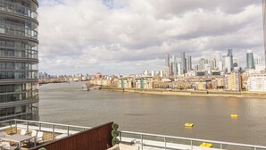 A river with a cityscape in the background, a modern building with balconies, and a clear sky. - Greenwich Apartment Near Cutty Sark and Paid Parking (London)
