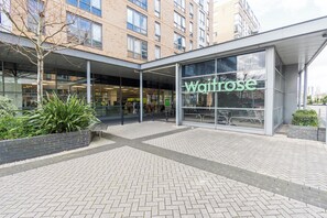 A modern building with a large glass facade and the name 'Waitrose' prominently displayed. - Greenwich Apartment Near Cutty Sark and Paid Parking (London)