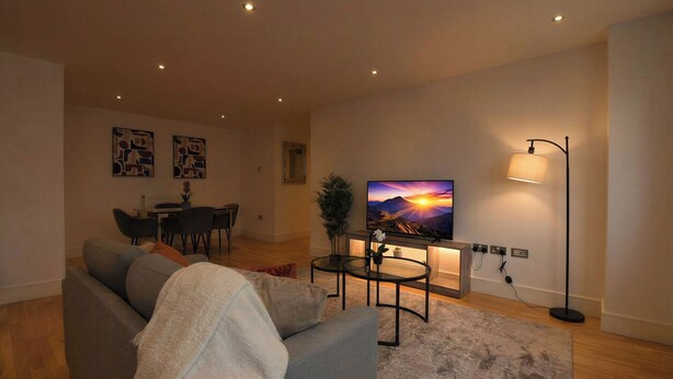 A living room with a sofa, a TV, a floor lamp, and a dining area. - Greenwich Apartment Near Cutty Sark and Paid Parking (London)