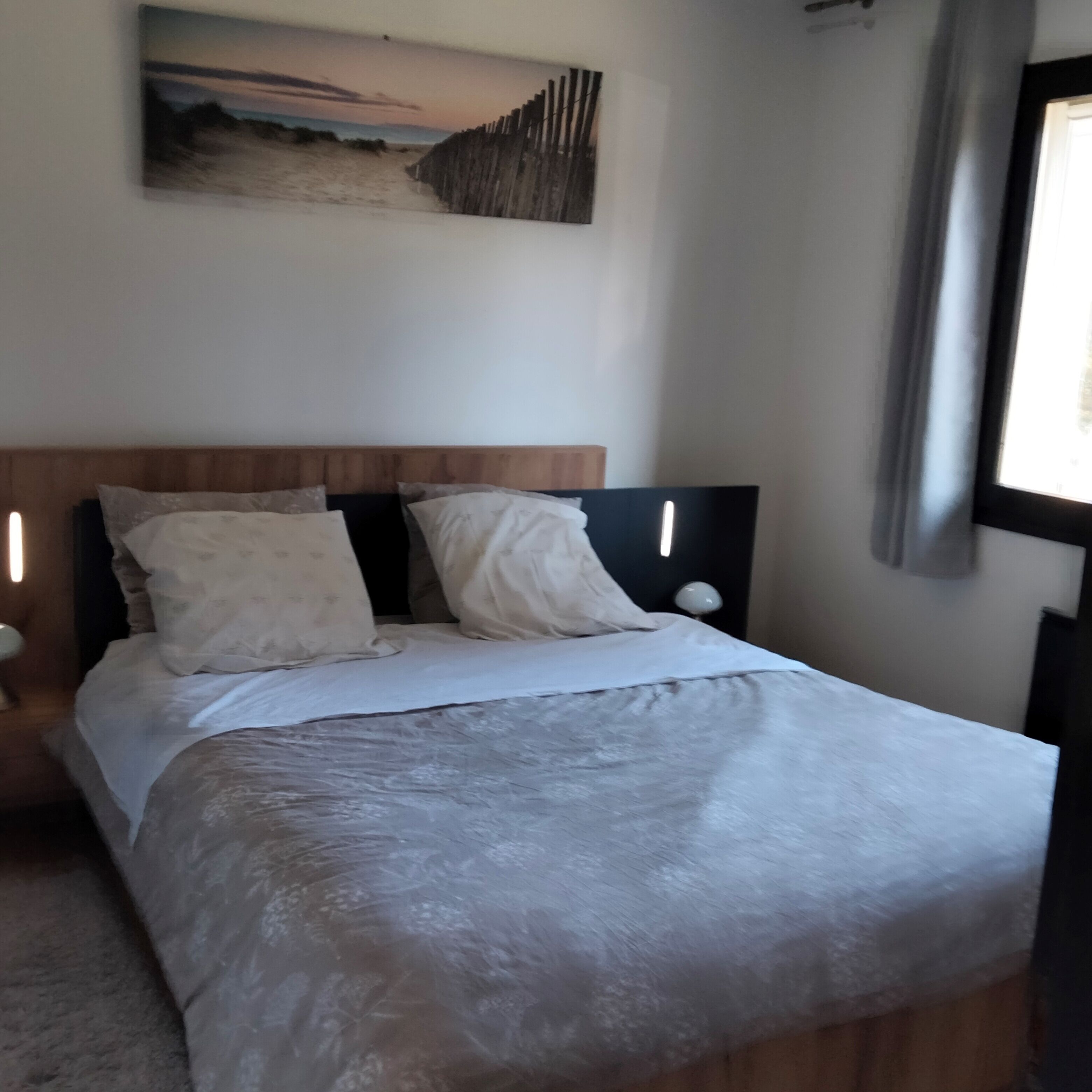 A bed with a wooden headboard, two pillows, and a white bedspread.