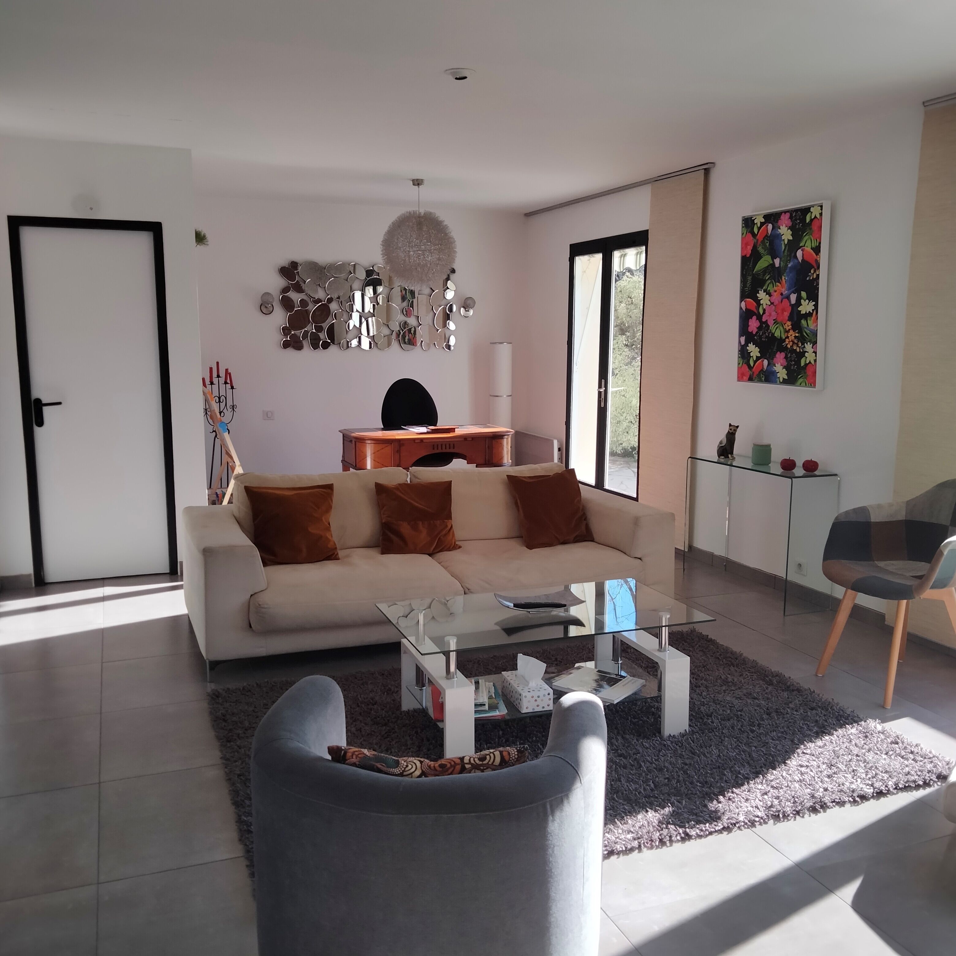 Ett modernt vardagsrum med en soffa, ett soffbord och en vägg dekorerad med speglar.