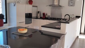 Une cuisine moderne avec un plan de travail noir, des armoires blanches et une hotte de cuisine en acier inoxydable.
