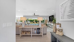 Ein modernes Wohnzimmer mit Sofa, Couchtisch und Esstisch. Durch die Glastüren ist ein Pool zu sehen.