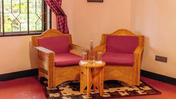 Habitación de esquina con sillones de mimbre, una mesita de madera y un tapete estampado.