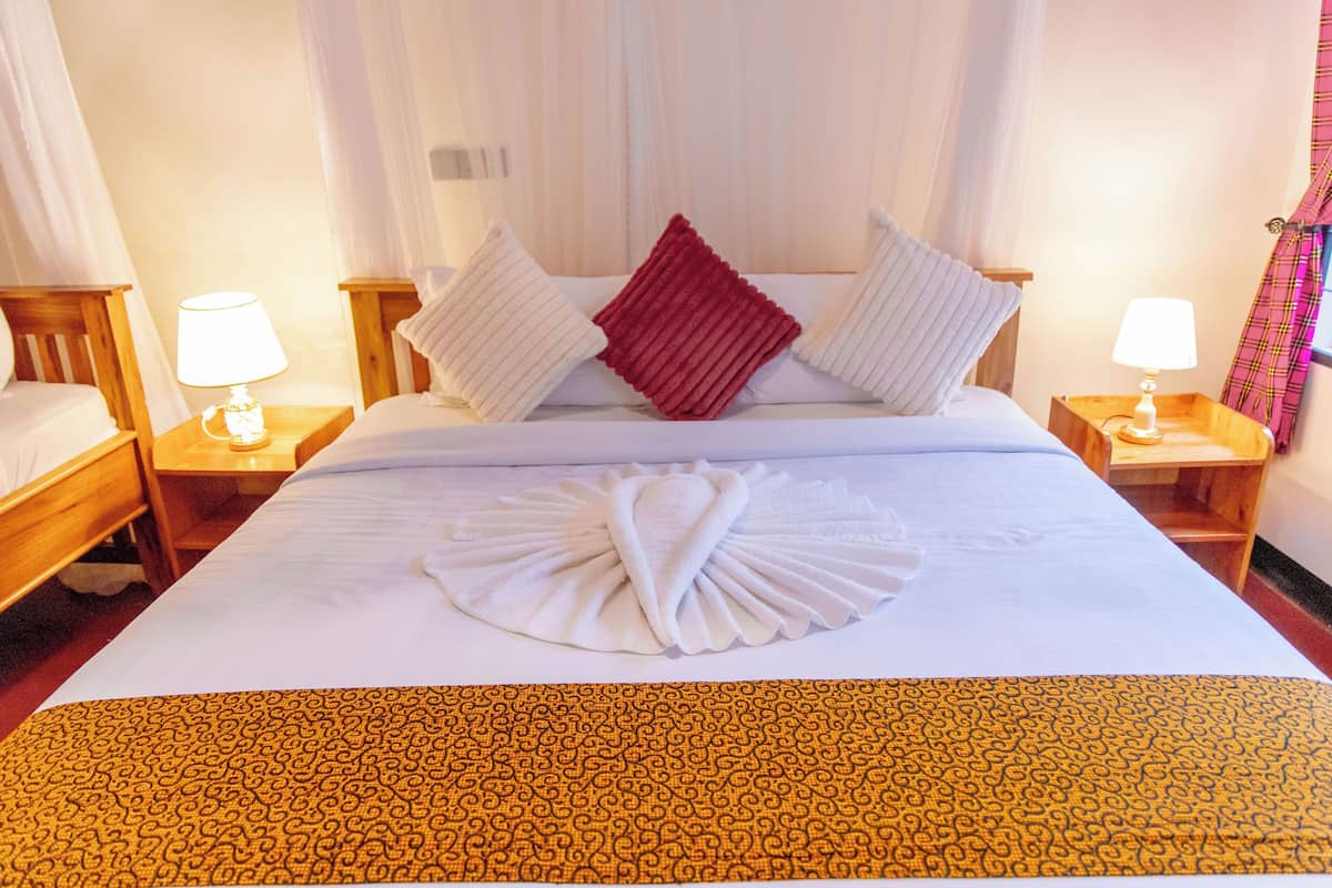 Une chambre d’hôtel avec un lit bien fait, deux tables de chevet avec des lampes et une fenêtre avec des rideaux.