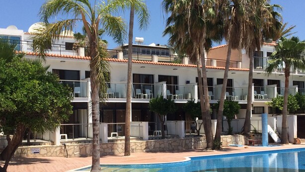 Um hotel com piscina, palmeiras e telhado telhado.