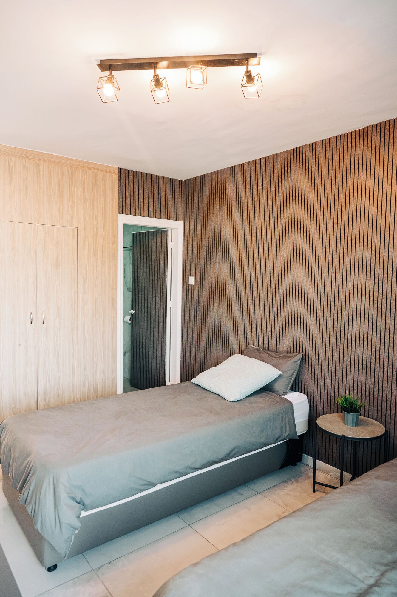 Un dormitorio con cama, mesita de noche, armario y puerta.