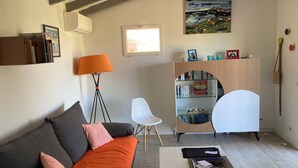 En stue med sofa, sofabord, reol, gulvlampe og et vindue.