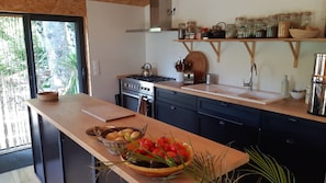 A kitchen with a wooden countertop, a stove, a sink, and a window with a view of greenery. - House Chalet isolated in the forest (Lespinassière)