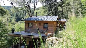 A wooden cabin with a deck, two windows, and a small porch area. - House Chalet isolated in the forest (Lespinassière)