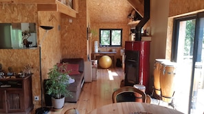 Un intérieur en bois comprenant un canapé, une table à manger, un grand ballon d’exercice, un meuble rouge et une batterie.