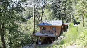 Une cabane en bois avec un toit en métal, une terrasse et un garage.