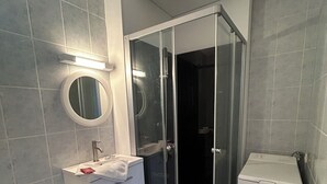 Ein Badezimmer mit Toilette, Waschbecken, Spiegel und einer Duschkabine.