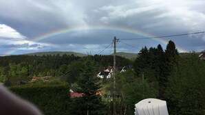 Punakatolla varustettu talo, jonka ympärillä on puita ja taustalla kohoaa kukkula.