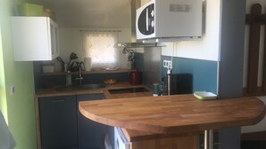Kompakti keittiö, jossa on mikroaaltouuni, pesuallas ja puinen työtaso.