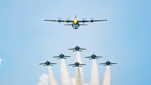 Een groot vliegtuig met een propeller en een kleiner vliegtuig in formatie.
