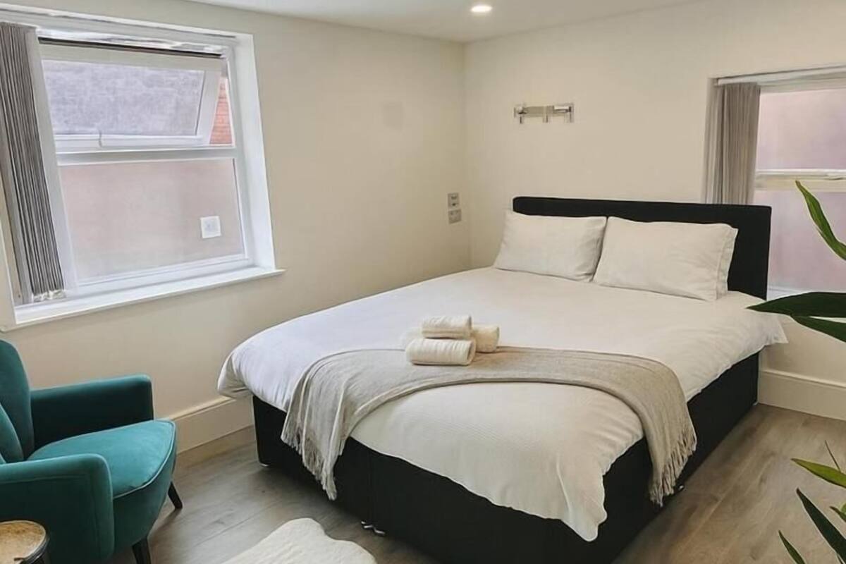 Une chambre à coucher avec un lit, une chaise, une fenêtre et une plante.